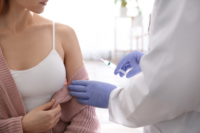 Doctor giving injection to patient in hospital, closeup. Vaccination concept