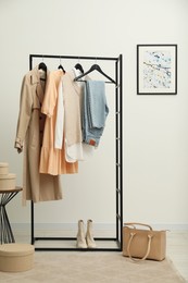 Photo of Rack with different stylish women's clothes, boots and bag indoors
