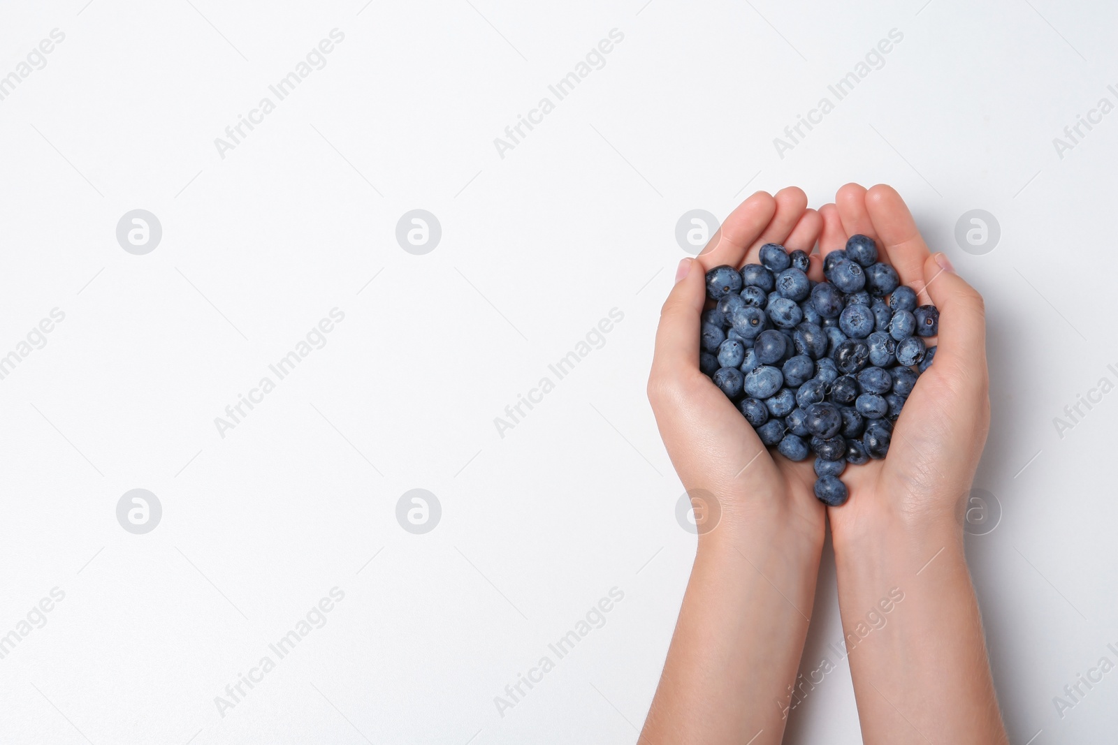 Photo of Woman holding juicy fresh blueberries on white background, top view. Space for text