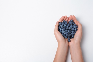 Woman holding juicy fresh blueberries on white background, top view. Space for text