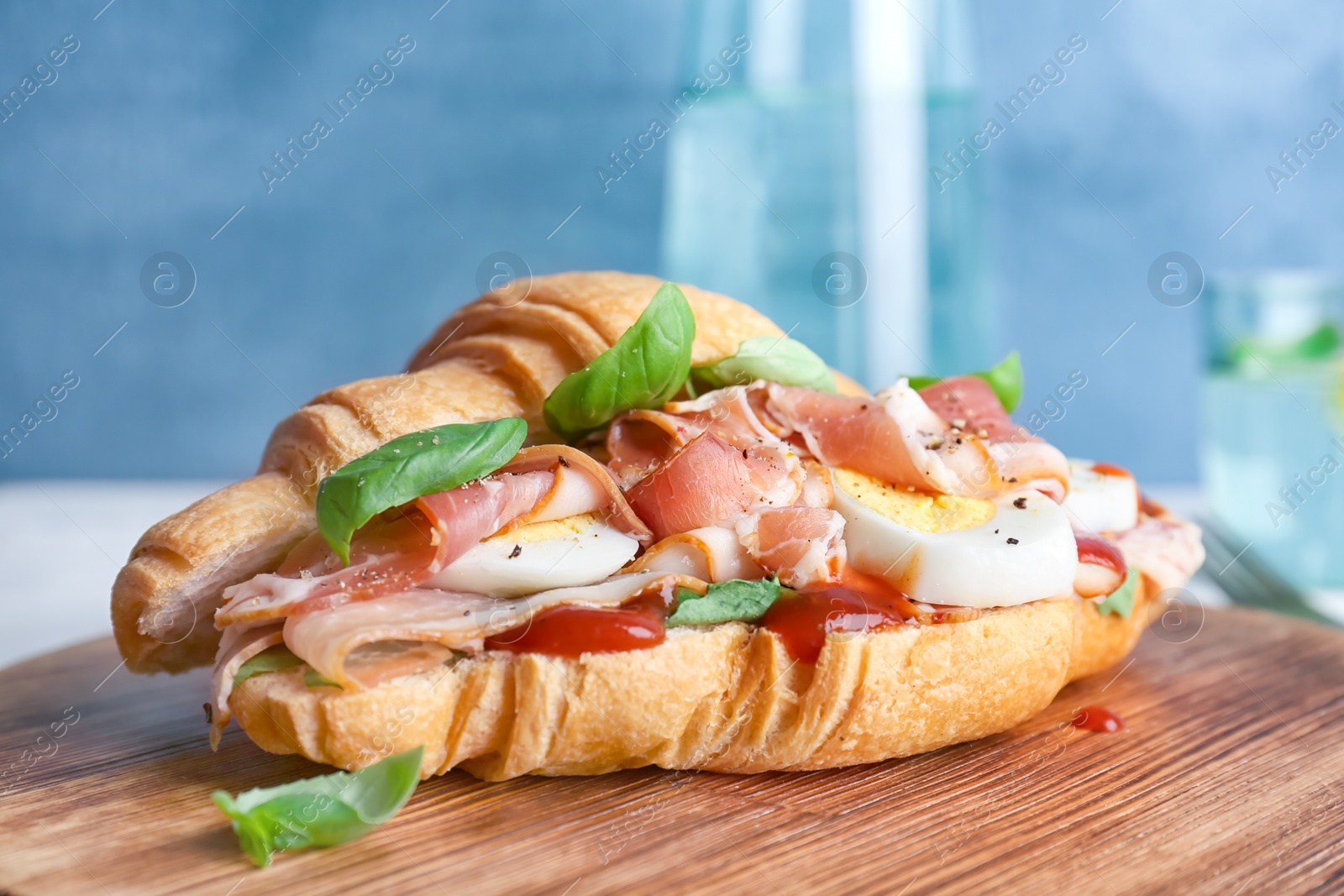 Photo of Tasty croissant sandwich with bacon on table