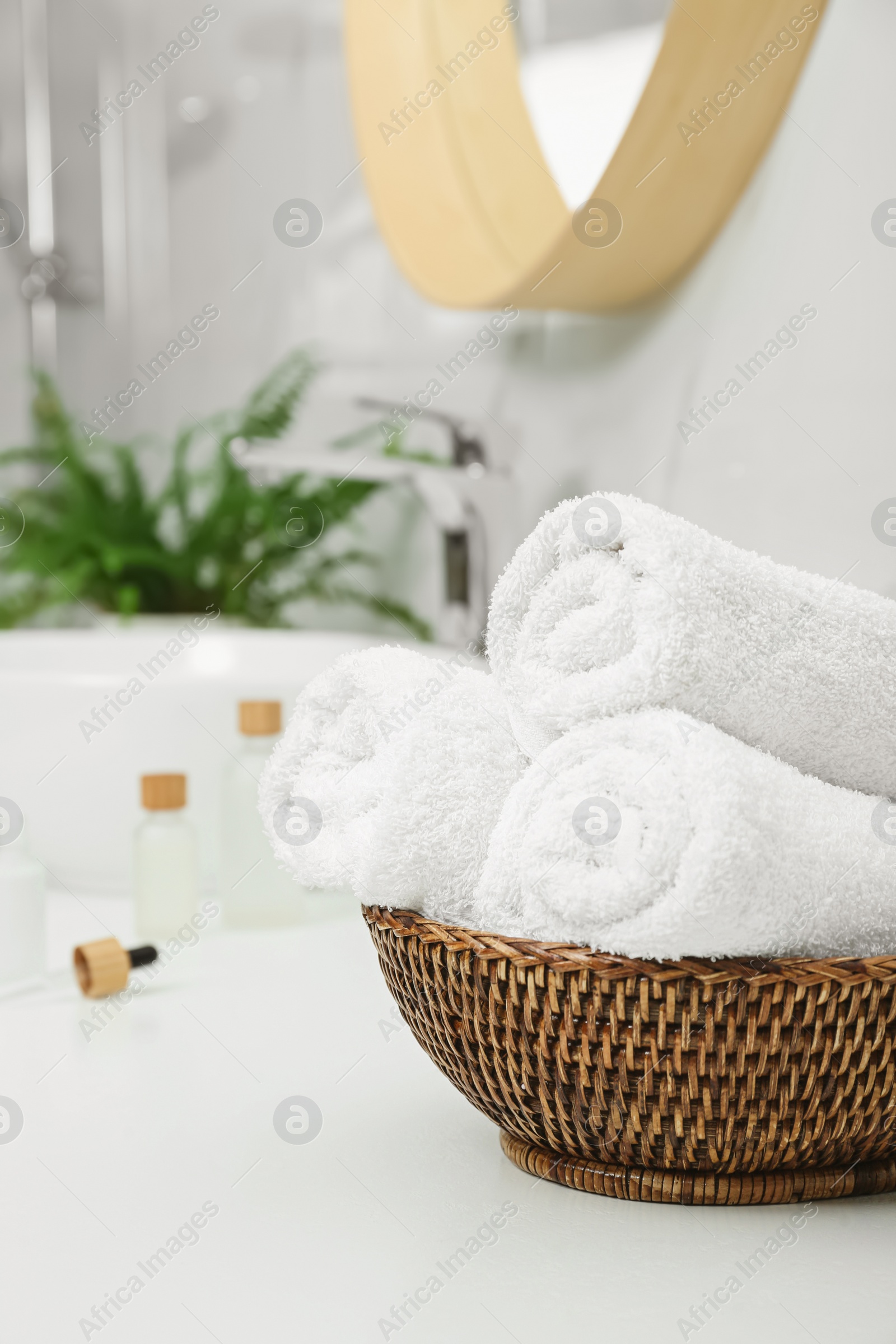 Photo of Rolled bath towels in wicker bowl indoors