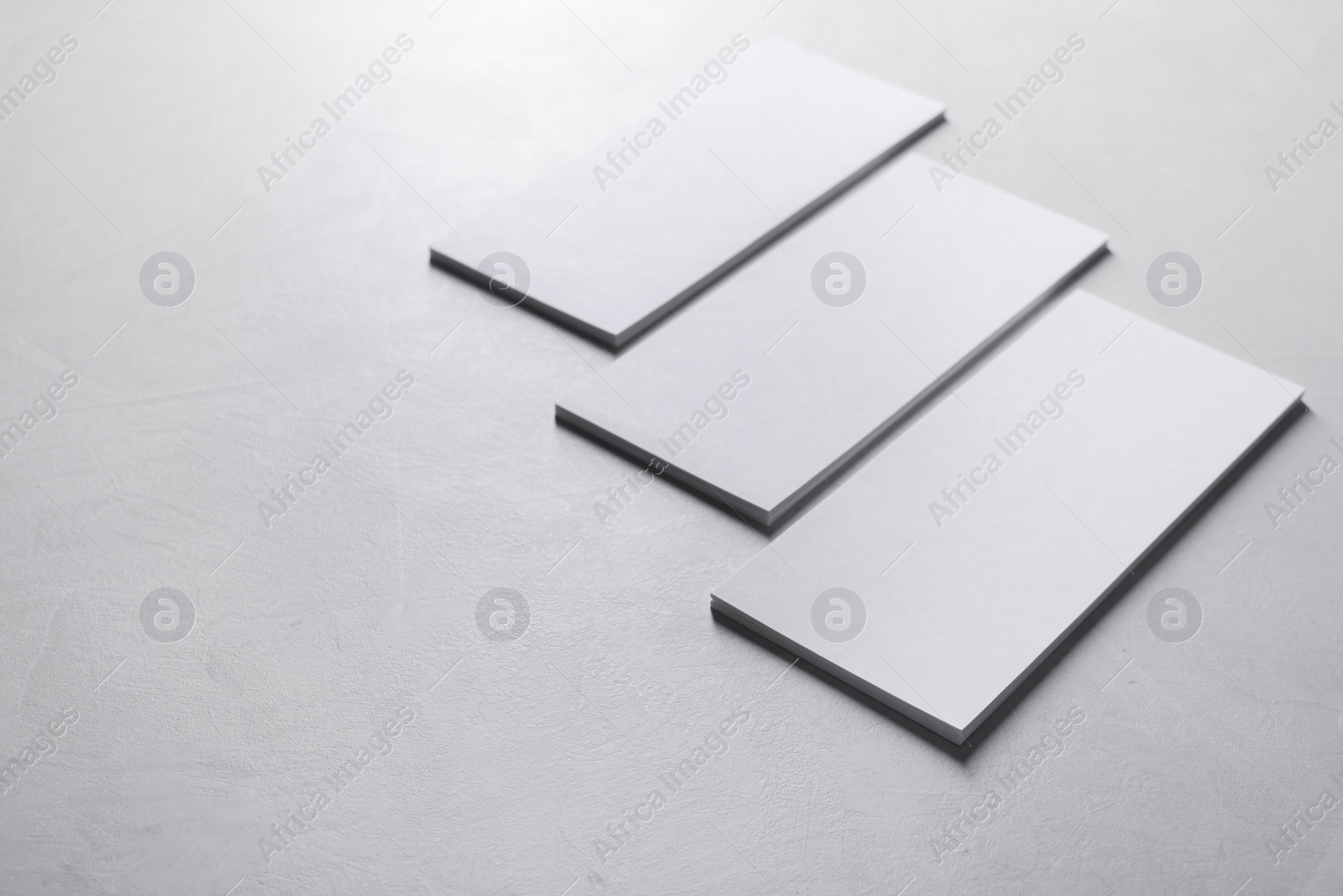 Photo of Blank business cards on light grey textured table, closeup. Mockup for design