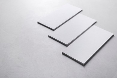 Blank business cards on light grey textured table, closeup. Mockup for design