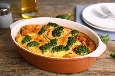 Photo of Tasty broccoli casserole in baking dish on wooden table