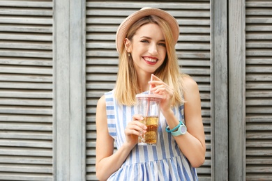 Photo of Young woman with cup of tasty lemonade near wooden wall