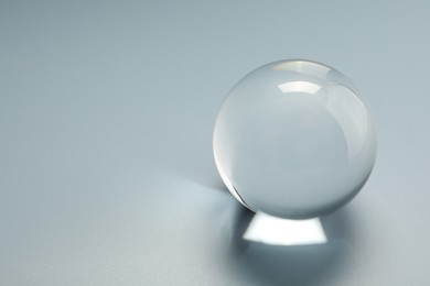 Photo of Transparent glass ball on light grey background. Space for text