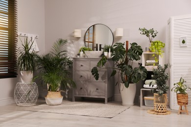 Photo of Stylish bathroom interior with modern furniture and beautiful green houseplants