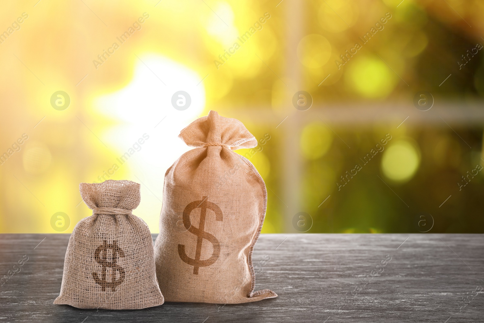 Image of Burlap bags with dollar signs on grey stone table indoors