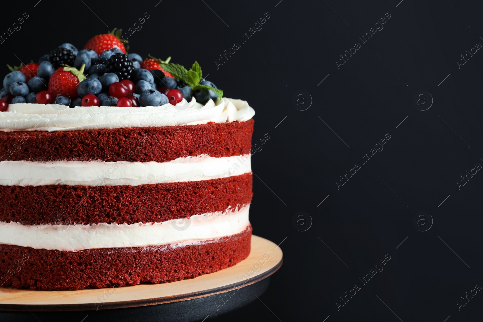 Photo of Stand with delicious homemade red velvet cake and space for text on black background