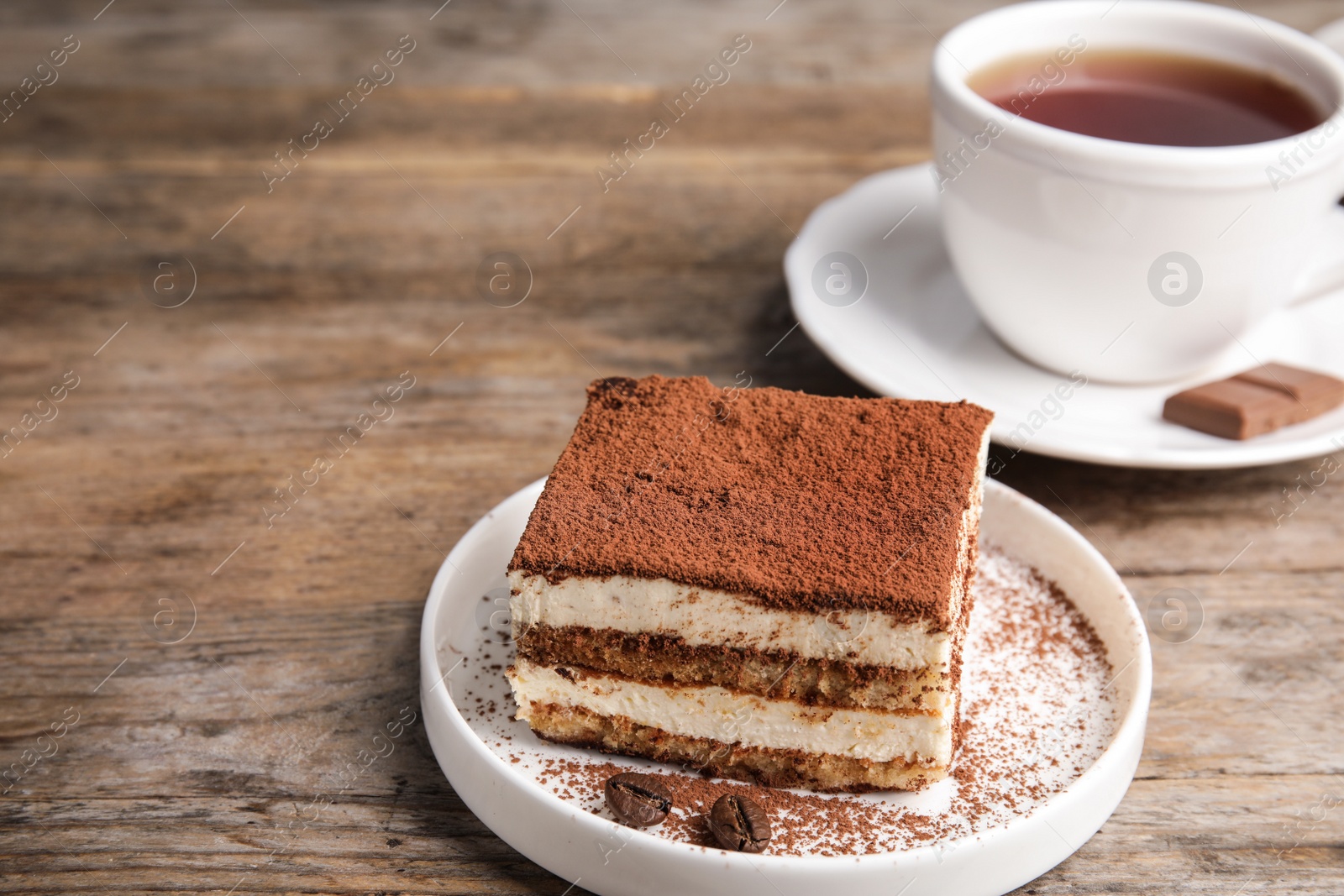 Photo of Composition with tiramisu cake and tea on wooden table, space for text