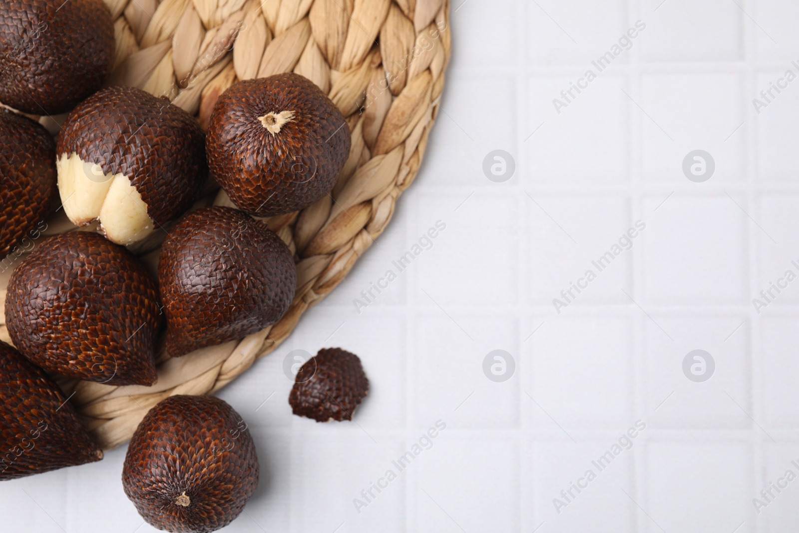 Photo of Fresh salak fruits on white tiled table, top view. Space for text