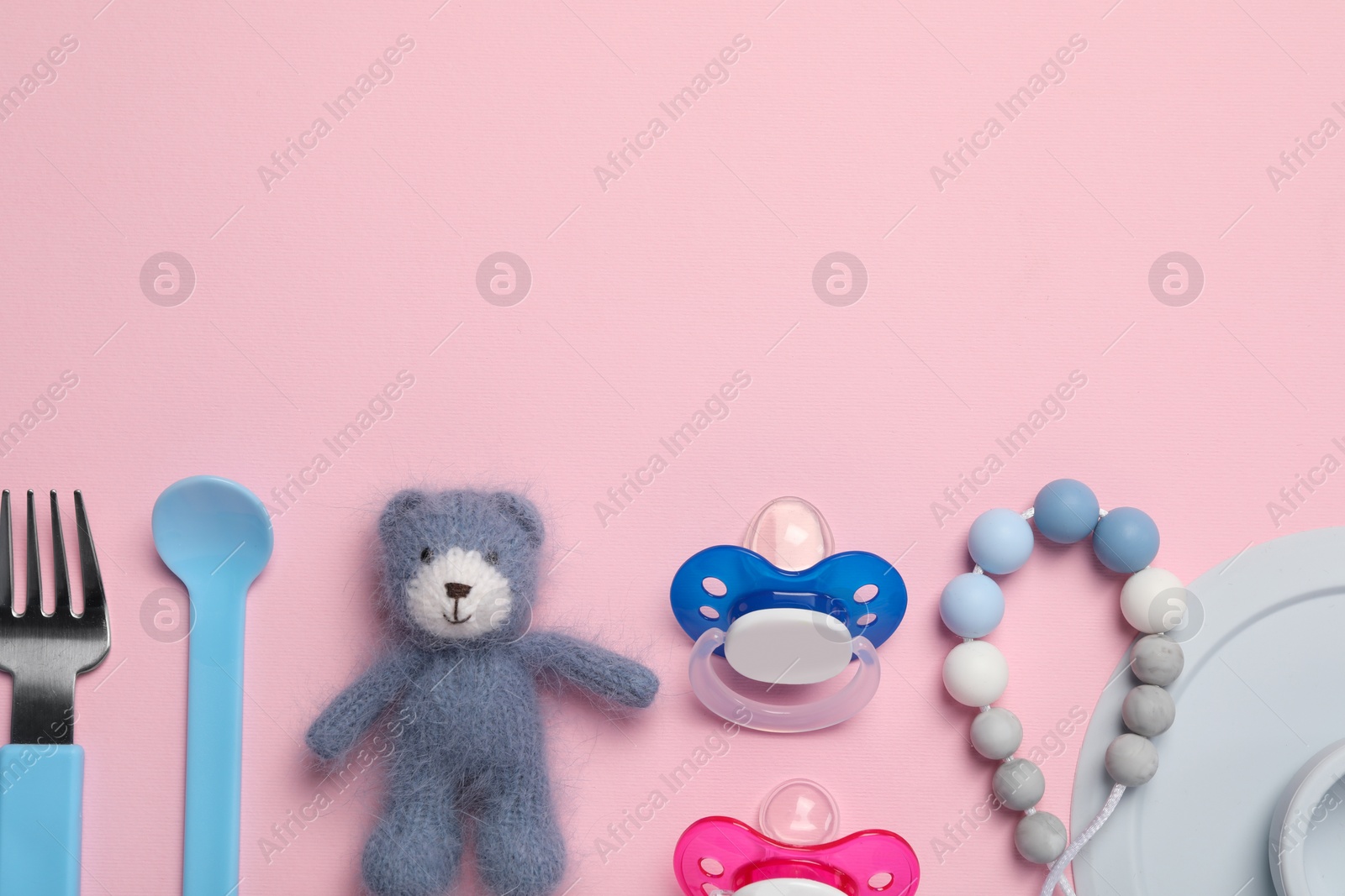 Photo of Flat lay composition with pacifiers and other baby stuff on pink background. Space for text