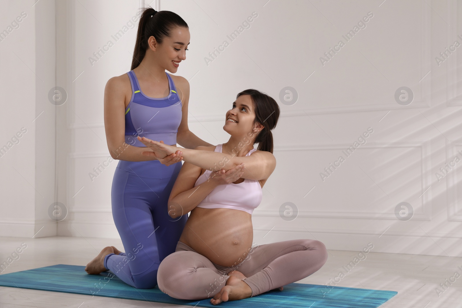 Photo of Trainer working with pregnant woman in gym. Preparation for child birth