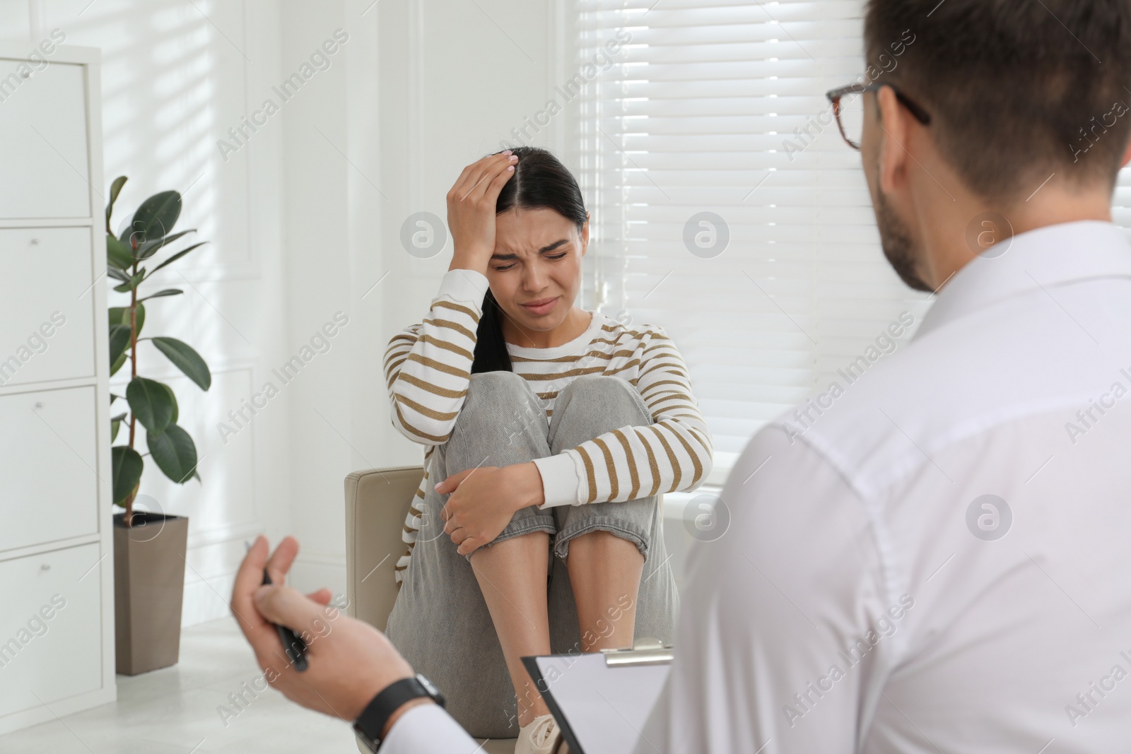 Photo of Psychotherapist working with drug addicted young woman indoors