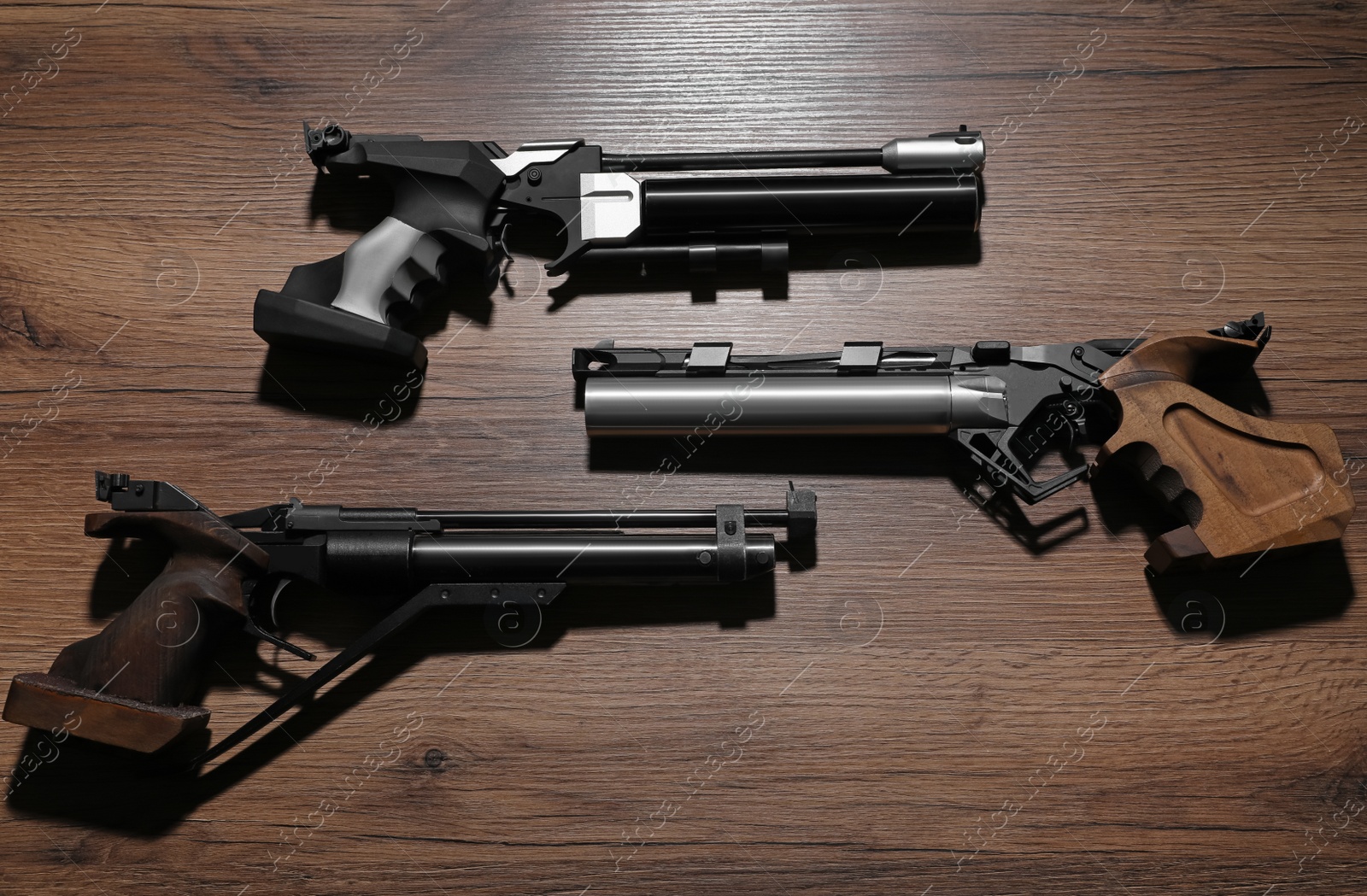 Photo of Different pistols on wooden table. Gun shooting sport