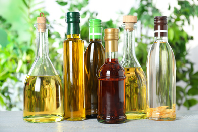 Photo of Different sorts of cooking oil in bottles on white wooden table
