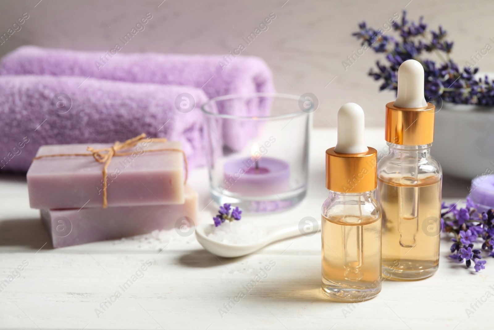 Photo of Composition with bottles of essential oil and lavender flowers on white wooden table