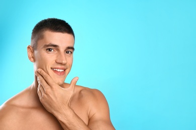 Handsome young man after shaving on light blue background, space for text