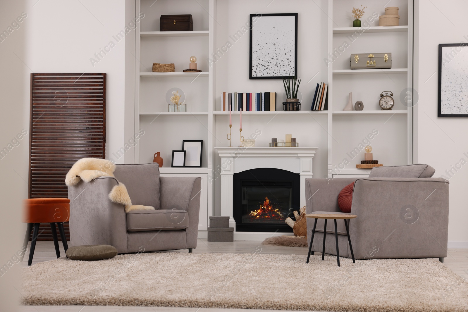 Photo of Comfortable armchairs, fireplace and shelves in living room. Interior design