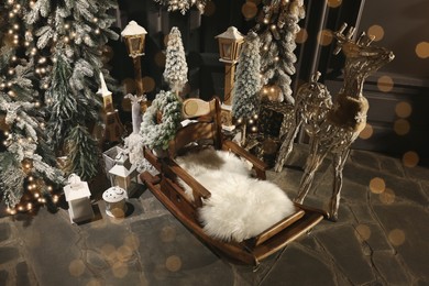 Photo of Wooden sleigh, lanterns, deer and Christmas decor on floor