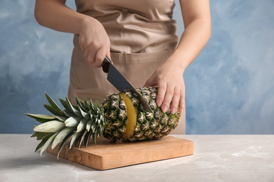 Photo of Woman cutting fresh pineapple on wooden board