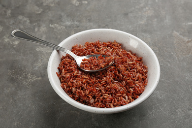 Photo of Tasty brown rice in bowl on grey table