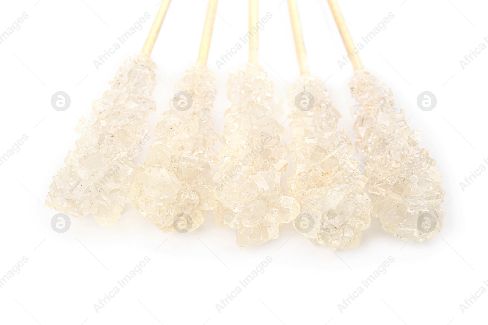 Photo of Wooden sticks with sugar crystals isolated on white, closeup. Tasty rock candies