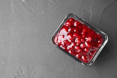 Photo of Fresh cranberry sauce in glass bowl on gray textured table, top view. Space for text