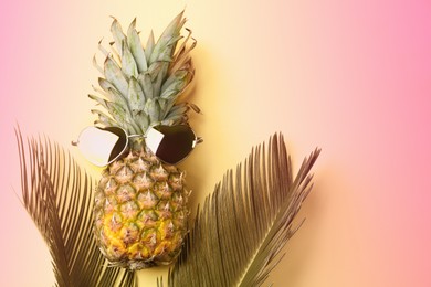 Pineapple with sunglasses and palm leaves on color background, flat lay. Summer party