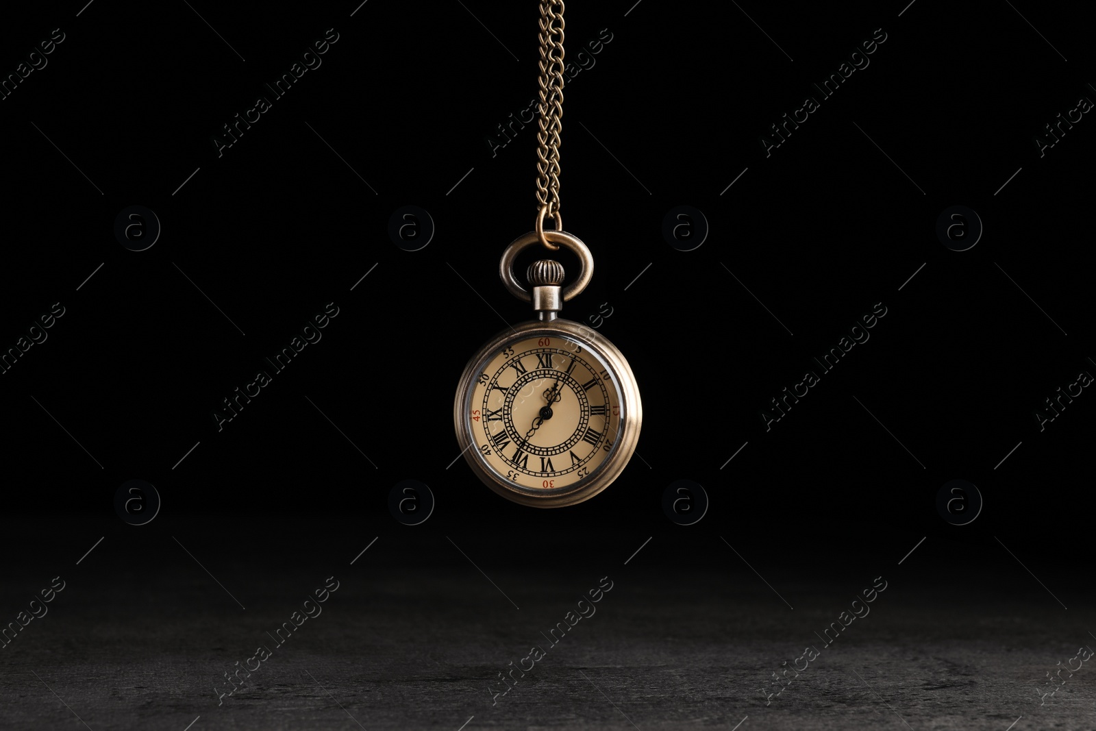 Photo of Stylish pendulum above table on black background. Hypnotherapy session