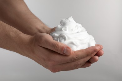 Photo of Man holding shaving foam on light grey background, closeup