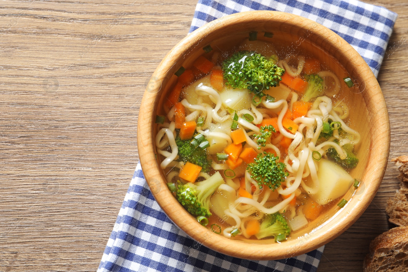 Photo of Bowl of fresh homemade vegetable soup on wooden background, flat lay. Space for text