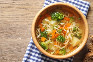 Photo of Bowl of fresh homemade vegetable soup on wooden background, flat lay. Space for text