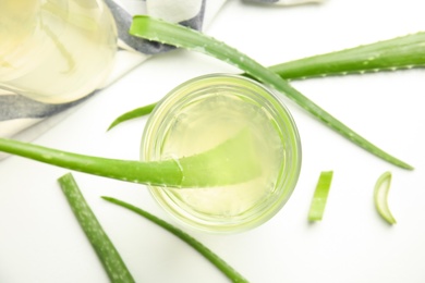 Photo of Fresh aloe drink in glass and leaves on white background, flat lay