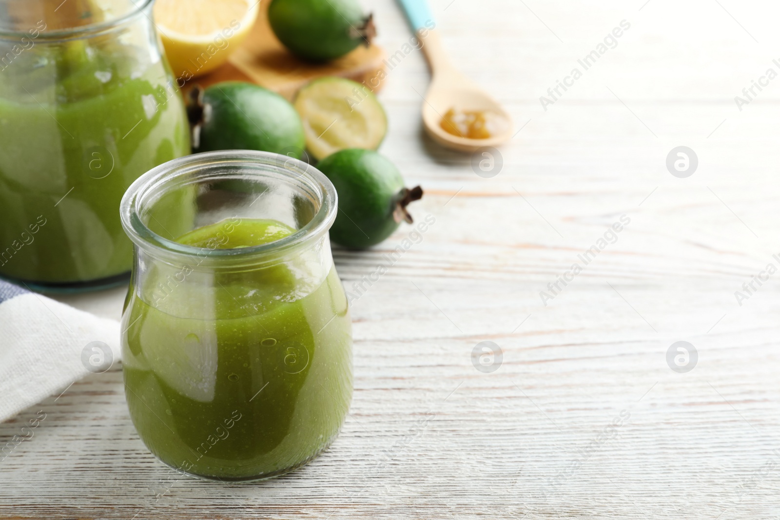 Photo of Feijoa jam on white wooden table. Space for text