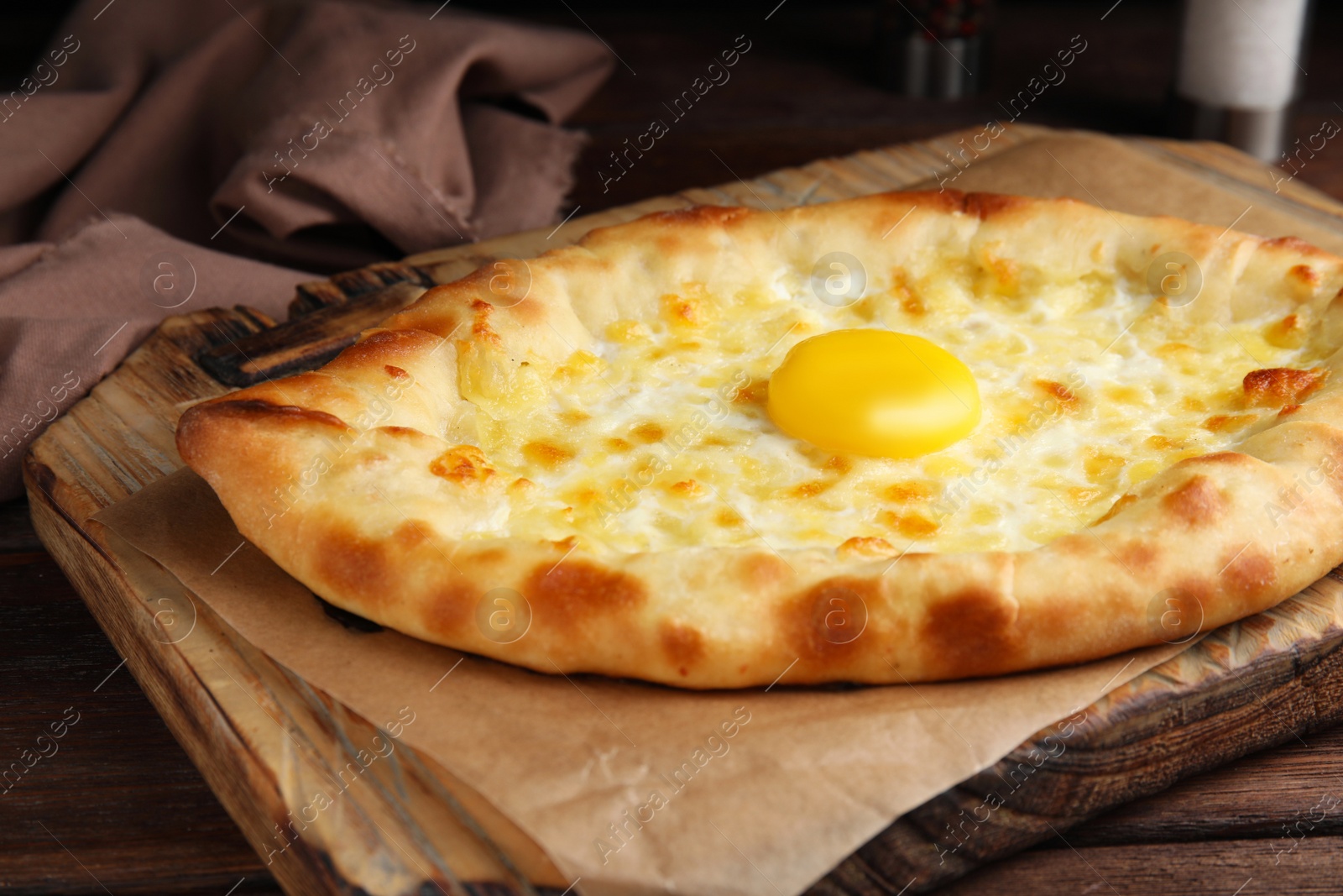 Photo of Fresh homemade khachapuri with cheese and egg on wooden table, closeup