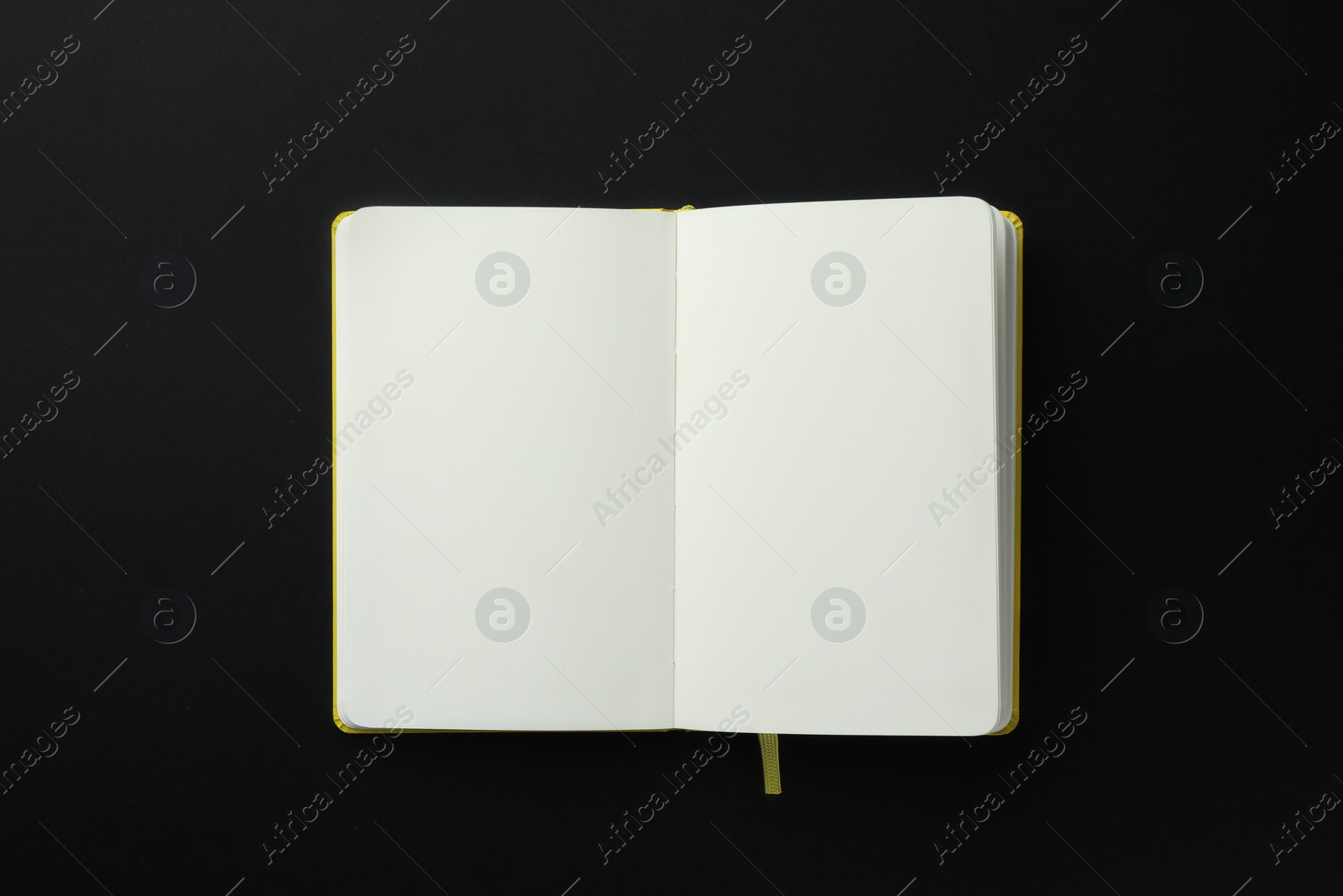 Photo of Open notebook with blank pages on black background, top view. Space for text