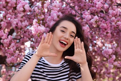 Photo of Happy woman near blossoming sakura tree on spring day