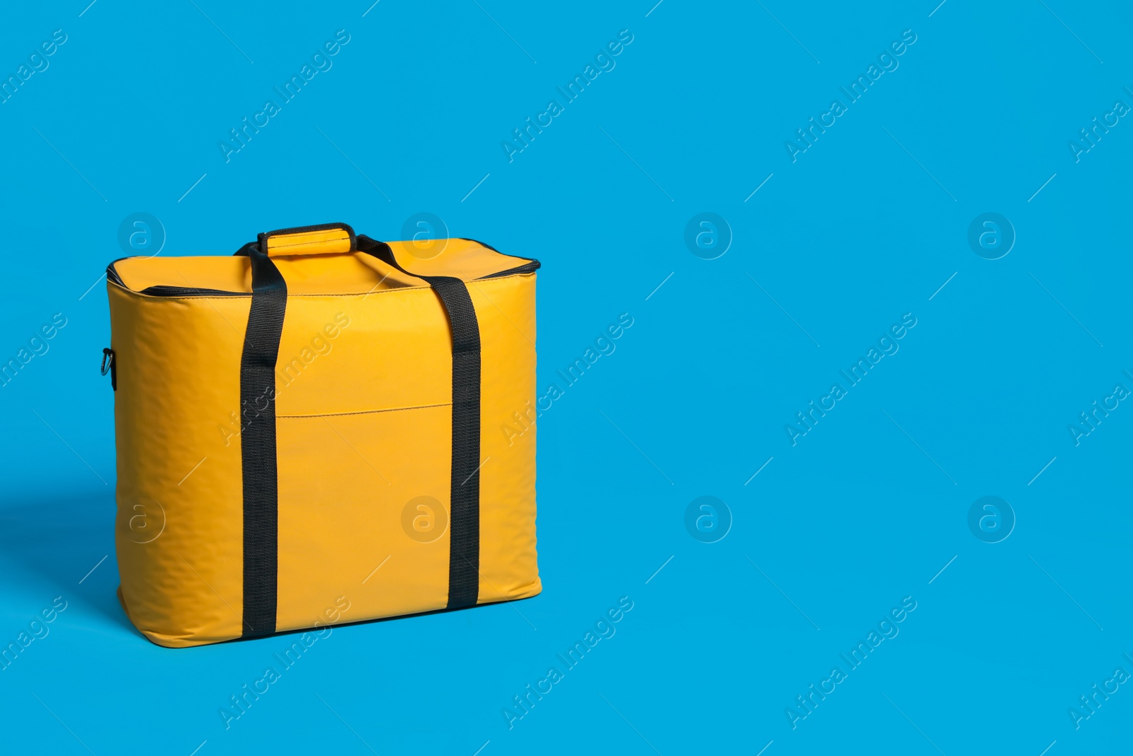 Photo of Modern yellow thermo bag on light blue background. Space for text