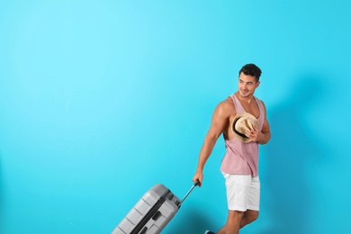 Photo of Young man walking with suitcase on color background. Space for text