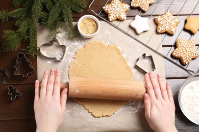 Making Christmas cookies. Woman rolling raw dough at wooden table, top view