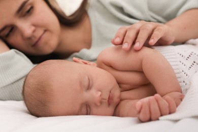 Photo of Young mother near her sleeping baby on bed, closeup