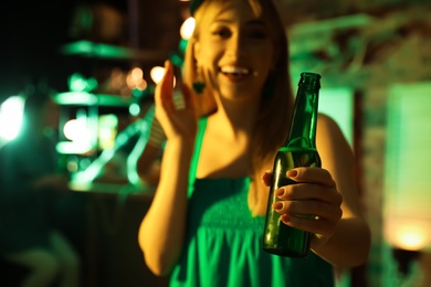 Photo of Woman with beer celebrating St Patrick's day in pub, focus on hand