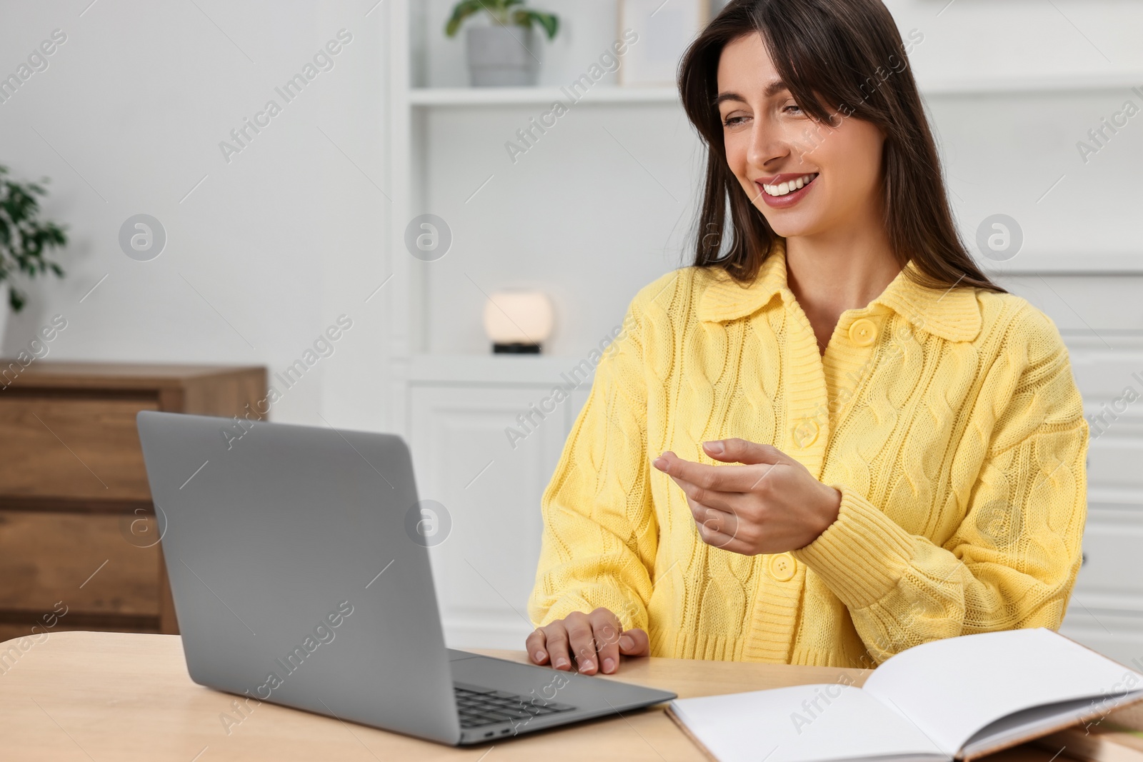 Photo of Happy woman having video chat via laptop at table indoors