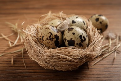 Photo of Nest with quail eggs on wooden table, closeup