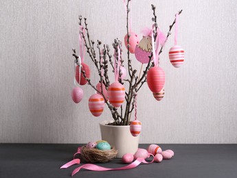 Photo of Beautiful willow branches with painted eggs and Easter decor on light grey wooden table