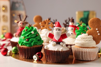 Photo of Different beautiful Christmas cupcakes and baubles on white table