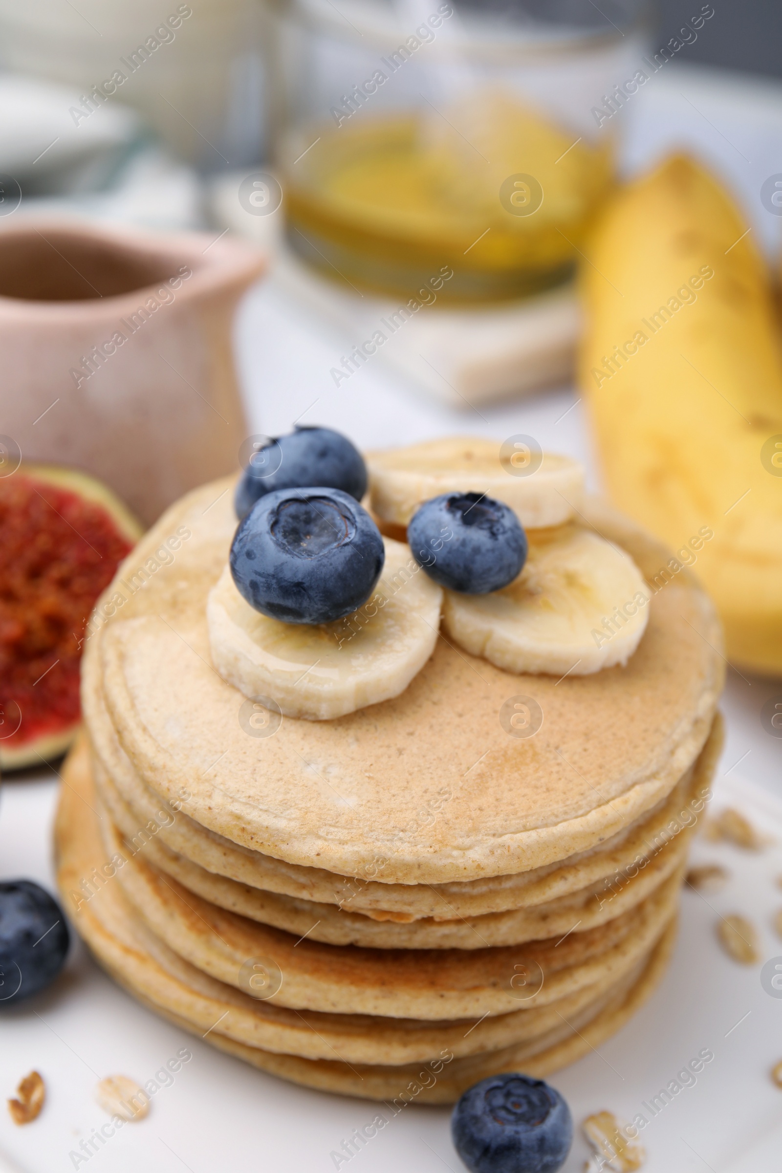 Photo of Tasty oatmeal pancakes with fruits on plate, closeup