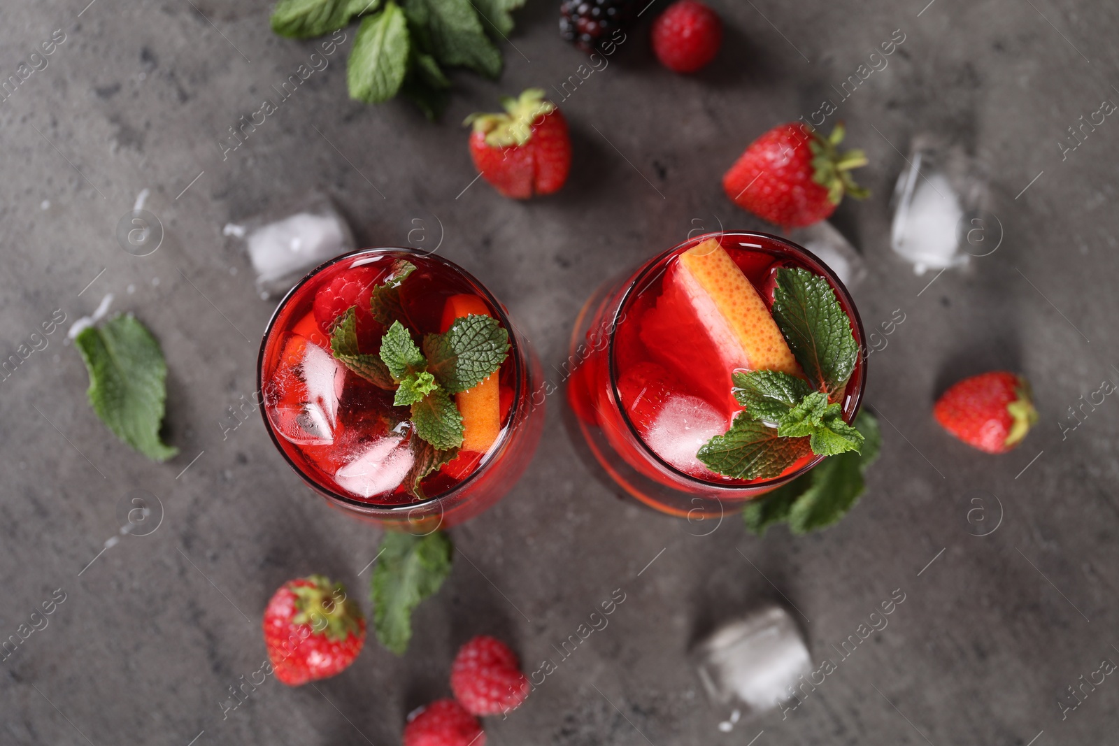 Photo of Delicious refreshing sangria, ice cubes and strawberries on grey table, flat lay